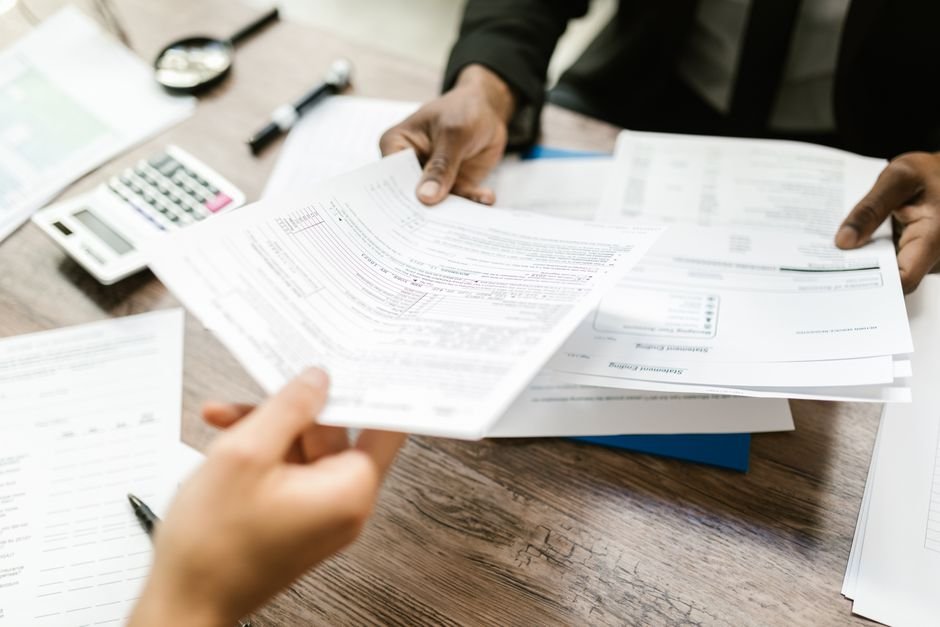 Insurance broker handing over comparison documents to a client reviewing matched health insurance quotes in the UAE