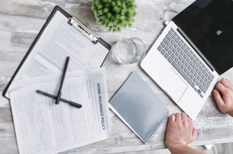 Health insurance renewal documents and laptop on a desk for checking the UAE table of benefits