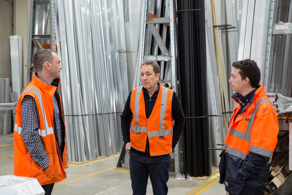 Warehouse team in safety gear discussing employee health cover