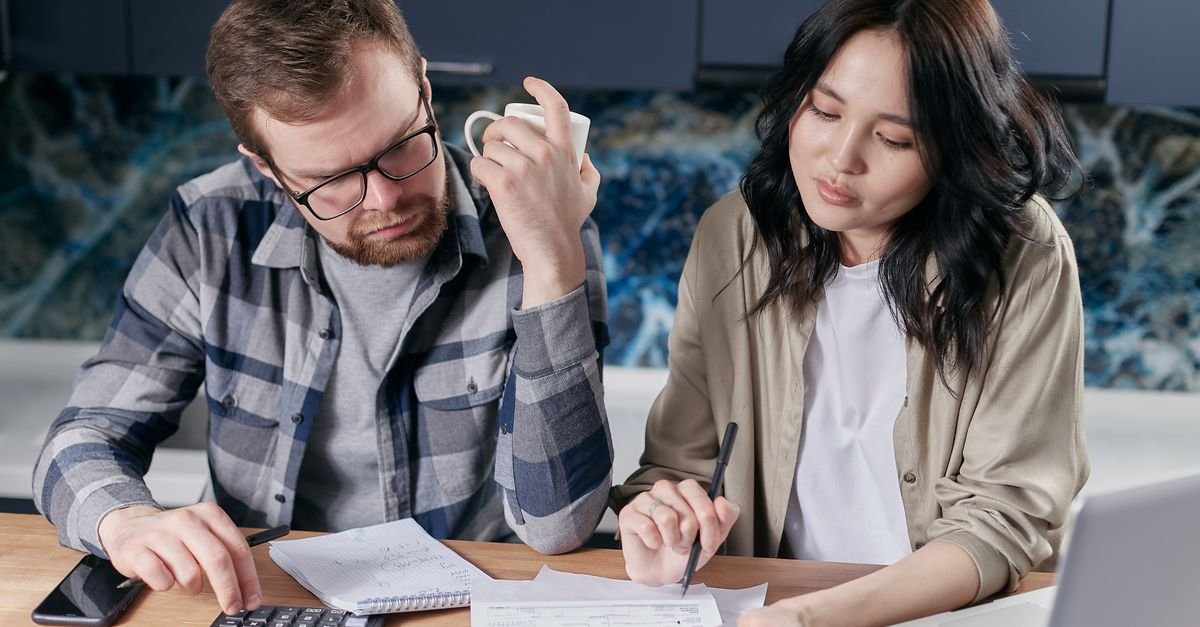 UAE couple reviewing a health insurance renewal notice with a calculator and laptop at home