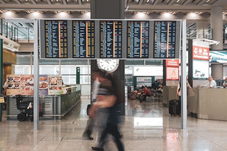 Travellers in an airport terminal checking departure screens during a flight disruption