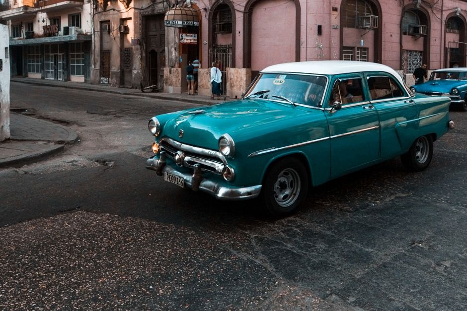 Older classic car driving on a city street, illustrating car insurance for old cars in the UAE