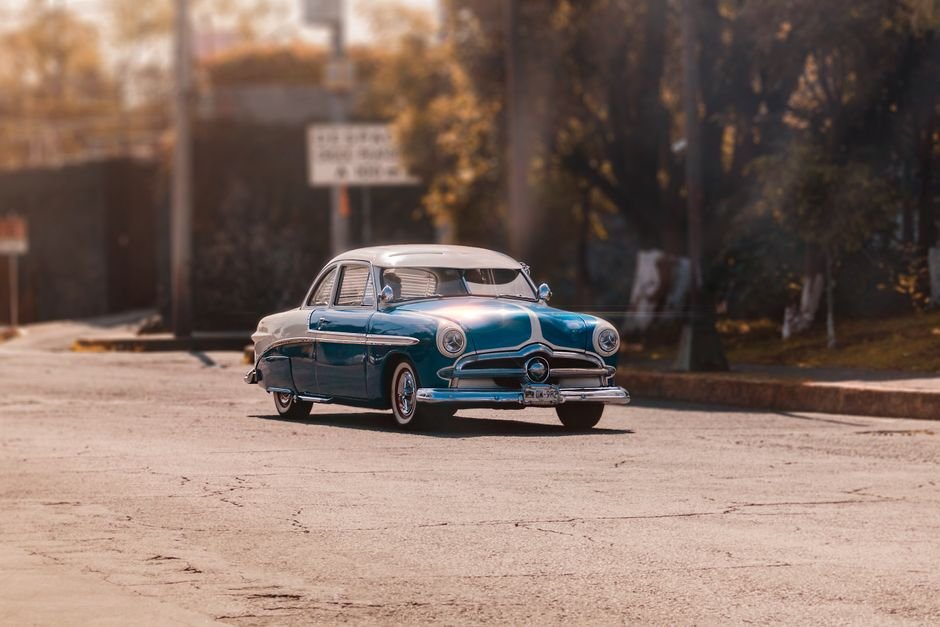 Vintage car on a sunlit street, an older vehicle that may need comprehensive or third-party insurance
